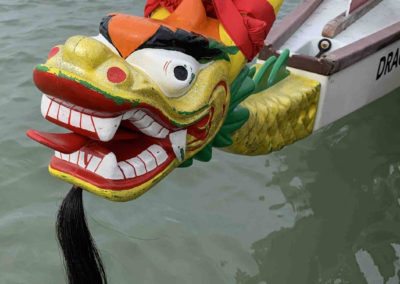 bright wooden dragon on bow of dragon boat. yellow, red, green, orange with black beard